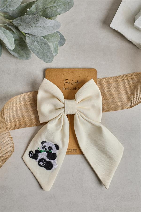 A beige bow tie with panda embroidery, presented on a card with 'Foux London' branding.